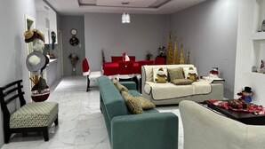 A modern living room with a sofa, chairs, and a dining area with a red table.