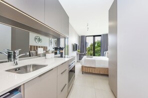 A modern hotel room with a large bathroom vanity, a bed, and a view of the outdoors. - Live Rosebank. Feel the Vibe. (Johannesburg)