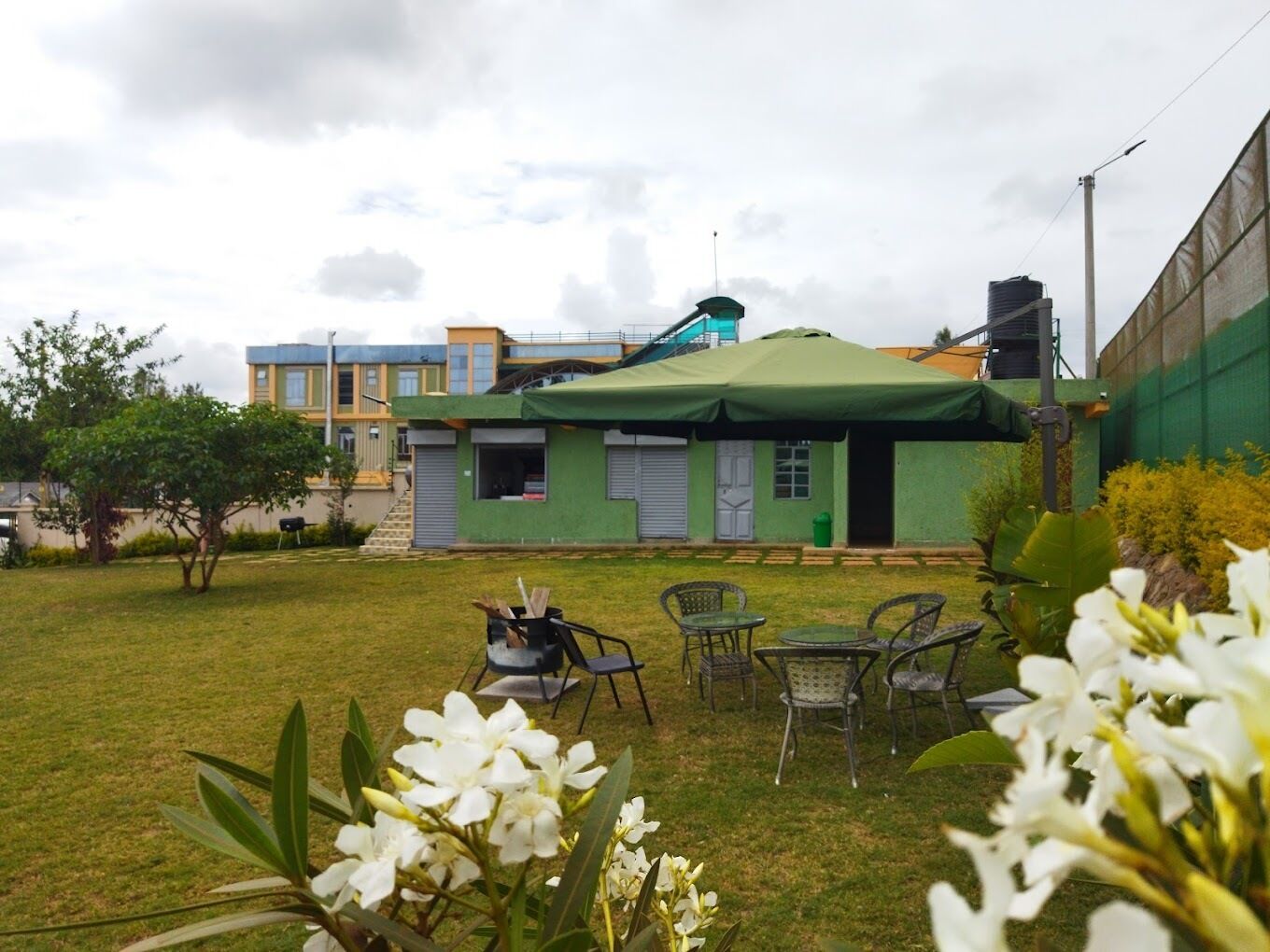 A courtyard with a green-roofed building, outdoor seating, and a view of other buildings in the background.