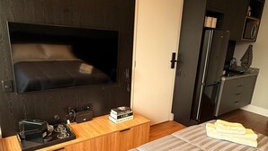 A modern bedroom with a large bed, a TV mounted on the wall, a wooden bedside table, and a built-in wardrobe. - New and Comfortable Flat • Olympic Village (São Paulo)