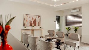 A modern living room with a marble floor, a console table with a vase of flowers, and a painting on the wall. - Nexus Xpress Hotel (Abuja)
