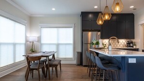 Una cocina moderna con armarios oscuros, un refrigerador de acero inoxidable y una isla central con taburetes de bar.