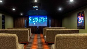 En biograf med mönstrade säten, en stor filmduk och en projektor.