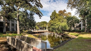 A serene courtyard with a pond, a wooden bridge, and lush greenery. - 70 Springwood Villas - 3BR/3 Bath (Hilton Head Island, SC)