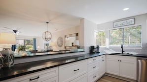 A modern kitchen with white cabinetry, black countertops, and a stainless steel dishwasher. - 70 Springwood Villas - 3BR/3 Bath (Hilton Head Island, SC)