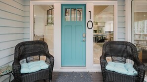 A turquoise door with the number 10, flanked by wicker chairs with cushions, on a porch with a doormat. - 10 Flamingo St - Forest Beach Serenity, Short Walk to the Beach 3Be 2Ba (Hilton Head Island)