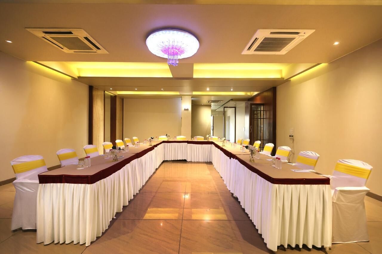 Un salón de conferencias con una larga mesa, sillas blancas y una araña.