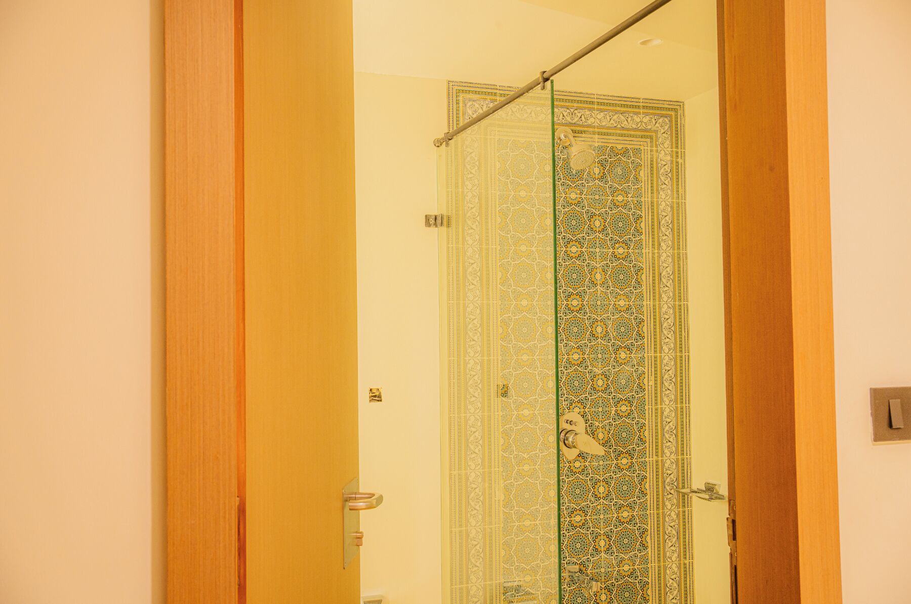 A bathroom with a shower, a glass door, and a wooden frame.