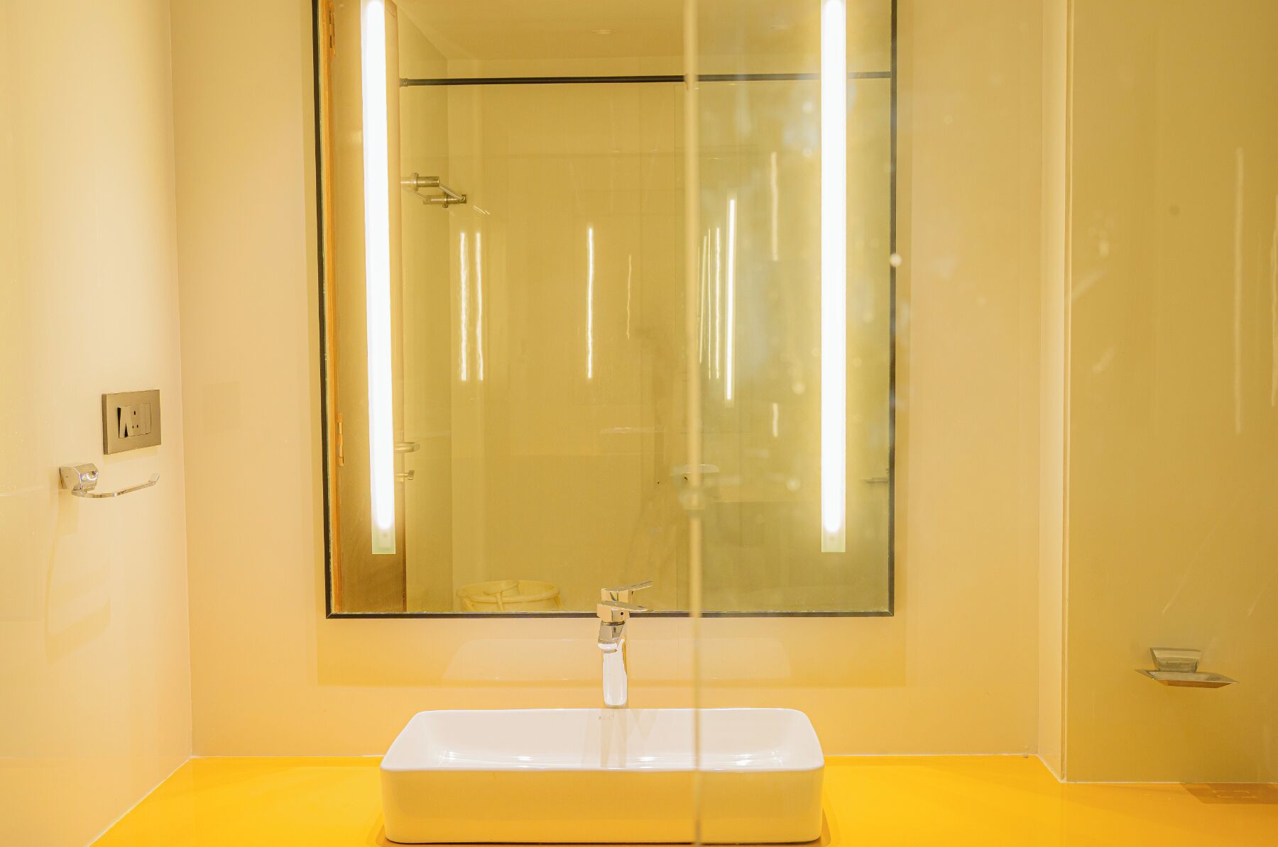 Une salle de bain avec un grand miroir, un lavabo blanc et une cabine de douche en verre.