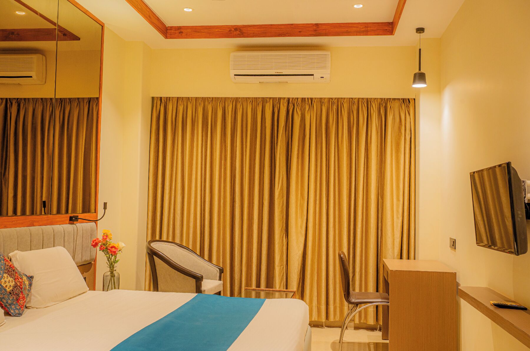 Une chambre d’hôtel équipée d’un lit, d’un bureau, d’une chaise, d’un climatiseur, d’un miroir et d’une télévision.