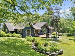 A modern house with a large deck, surrounded by lush greenery and a well-maintained lawn. - The Manor on the Ridge | Mt Snow 5 Min · Hot Tub (Dover)