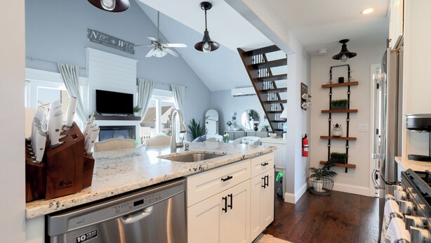 A modern kitchen with a dishwasher, a sink, and a built-in oven. There is a staircase leading to an upper level. - Waterfront Oasis Heated Pool, Dock & Outdoor Fun. 3 miles to LBI beaches! (Stafford Township)