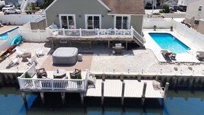 A residential property with a pool, outdoor seating, and a dock extending into the water. - Waterfront Oasis Heated Pool, Dock & Outdoor Fun. 3 miles to LBI beaches! (Stafford Township)