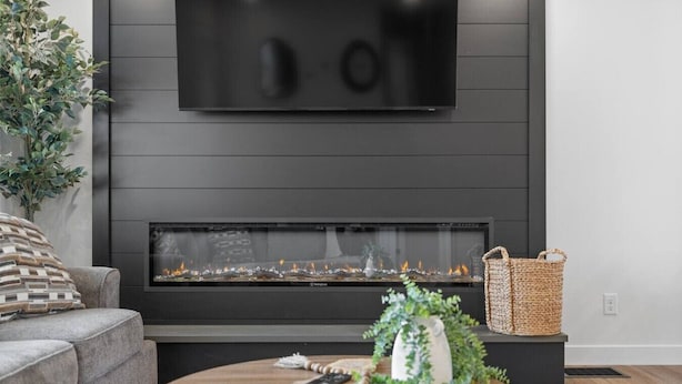A modern living room with a fireplace, a sofa, a coffee table, and a TV mounted on the wall. - 3 bed,2 bath Luxury & Private Turf Yard (Rapid City)