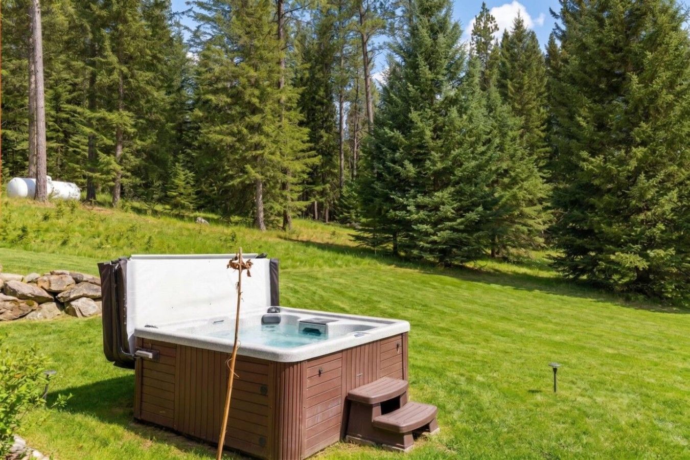 A hot tub in a grassy area with trees in the background.