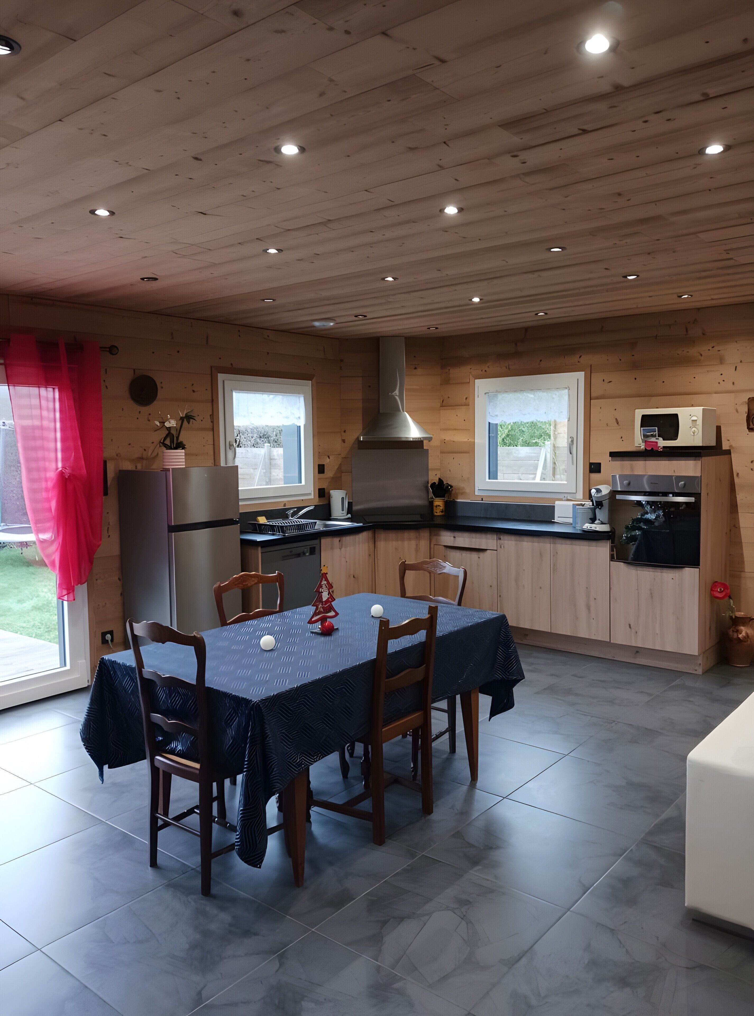 L’intérieur d’une cabane en bois comprend une table à manger, des chaises, une cuisine équipée d’une cuisinière, d’un four à micro-ondes et d’un réfrigérateur.