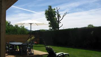 Une terrasse avec une table et des chaises, un toboggan et un parasol.