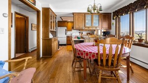 Una cocina con armarios de madera, una mesa de comedor con sillas y un ventanal con vistas.