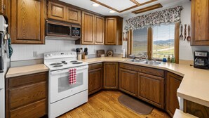 Una cocina con armarios de madera, una estufa blanca y un ventanal con vistas.