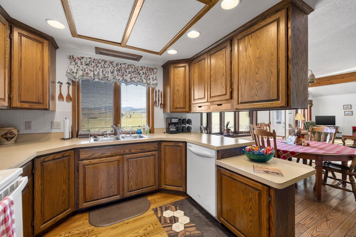 A kitchen with wooden cabinets, a built-in dishwasher, and a dining area with a table and chairs.