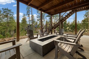 An outdoor deck with Adirondack chairs, a fire pit, and a staircase leading to a higher level. - Sleeps 14, Hot tub, OutdoorFireTable, HeatedGarage (Lead)