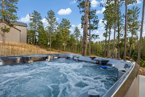 Ein Whirlpool, umgeben von hohen Kiefern und einem Gebäude im Hintergrund.