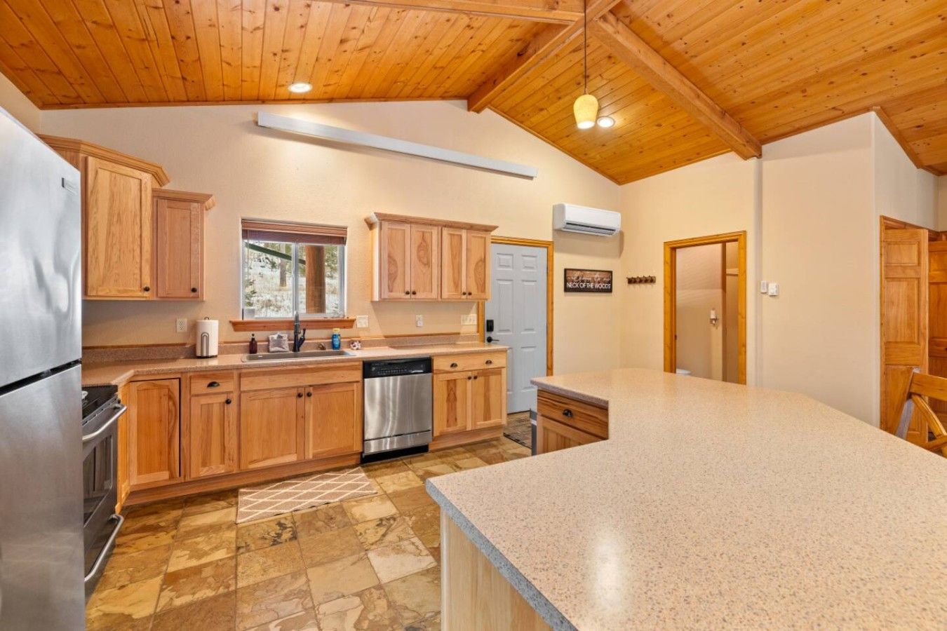 A kitchen with wooden cabinets, a stainless steel refrigerator, and a granite countertop.
