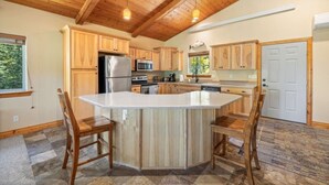 A kitchen with wooden cabinets, a central island, and a stone floor.