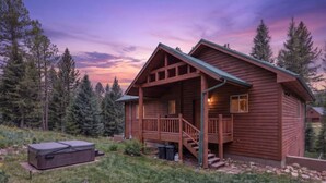 A wooden cabin with a porch, steps, and a hot tub.