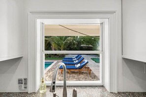 Un baño con vista a una zona de piscina, que incluye sillones de descanso y una piscina.