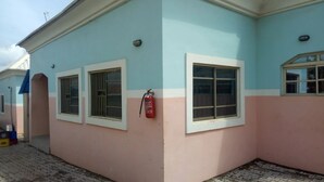 A building with a pink and blue facade, three windows, and a fire extinguisher mounted on the wall. - Mabala Millennium  Hotel (Abuja)
