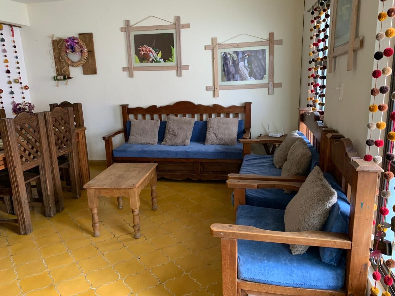 Una sala de estar acogedora con un sofá de madera, sillones azules y una mesa de centro de madera.