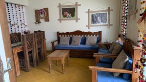 Ein gemütliches Wohnzimmer mit einer Holzsofa, passenden Sesseln, einem Couchtisch und einem Essbereich mit Holztischen und -stühlen.