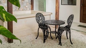 A patio with a round table and four chairs, a stone wall, and a wooden pergola. - Esencia Valladolid Hotel (Valladolid)