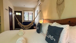 A hotel room with a bed, a hammock, a wooden headboard, and a wall decoration. - Esencia Valladolid Hotel (Valladolid)