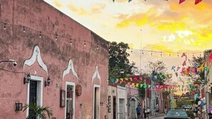 A street with buildings, string lights, and colorful flags. - Esencia Valladolid Hotel (Valladolid)