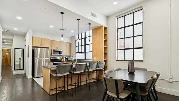 Una cocina moderna con una isla central, taburetes de bar y una mesa de comedor con sillas.