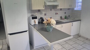 Een keuken met witte kastjes, een aanrecht, een spoelbak en een raam.