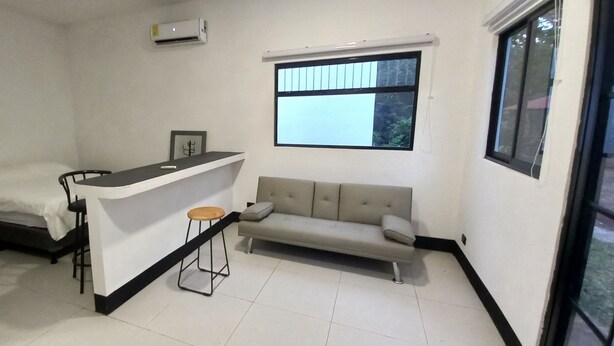 A compact room with a bed, a small bar area, a sofa, and a window providing a view. - Nature Sanctuary Studio #1 w/ AC, Close to Tamarindo, Flamingo Beaches (Tamarindo)
