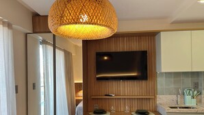 Ein modernes Hotelzimmer mit Essbereich, einem an der Wand montierten Fernseher und einer Küchenzeile.