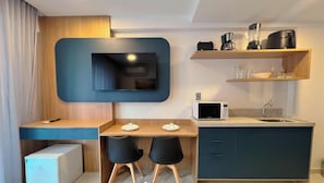 Una kitchenette moderna con microondas, cafetera y televisor de pantalla plana montado en la pared.