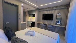 Ein Hotelzimmer mit Bett, Schreibtisch, Fernseher und einer Küchenzeile.