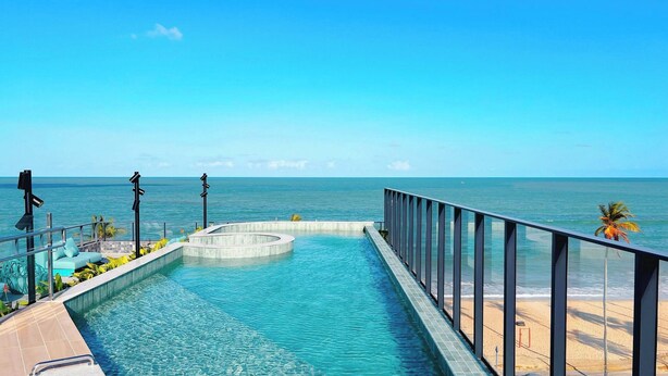 Ein Pool mit Blick auf den Ozean, eine Palme und ein Strand.
