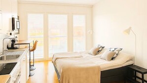A modern hotel room with a bed, bedside table, lamp, and a kitchenette area with a sink and stove. - Modern and cozy studio just a few minutes from Rovaniemi city center. (Rovaniemi)