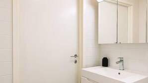 A bathroom with a white sink, a mirror, and a door. - Modern and cozy studio just a few minutes from Rovaniemi city center. (Rovaniemi)