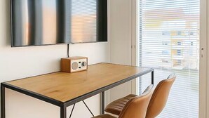 A modern room with a wooden table, a flat-screen TV mounted on the wall, a wooden radio, and two brown chairs. - Modern and cozy studio just a few minutes from Rovaniemi city center. (Rovaniemi)