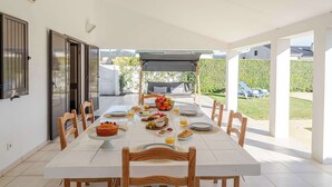 A dining area with a white table set for breakfast, including fruits, bread, and beverages. - Ma-la Beach House by HostWise (Marinhas)