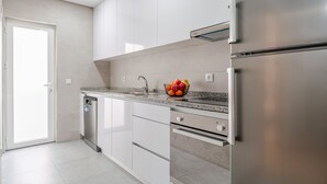 Een moderne keuken met witte kastjes, een roestvrijstalen koelkast, een vaatwasser en een granieten aanrecht.
