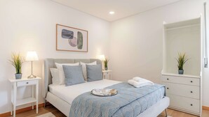 Een keurig opgemaakt slaapkamer met een bed, nachtkastjes, een dressing en een spiegel.