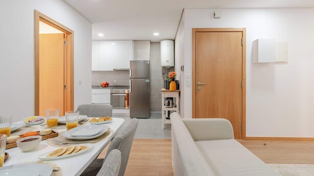 Een moderne keuken met witte kasten, een roestvrijstalen koelkast en een inbouwoven.
